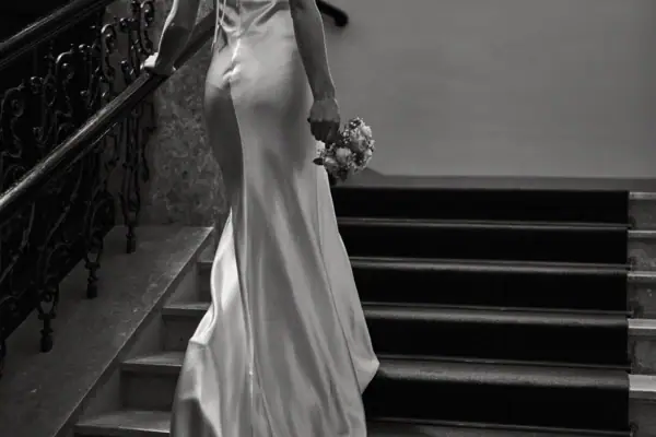 Una donna in abito bianco tiene un bouquet di fiori.