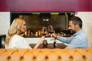 Un uomo e una donna sono seduti a un tavolo con dei bicchieri di vino.