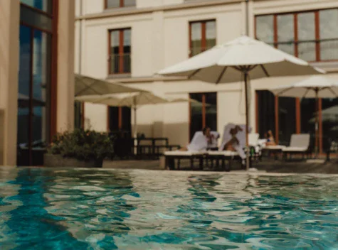 Piscina all'aperto con ombrelloni di fronte a un edificio.