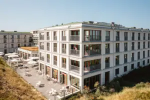 A-ROSA Sylt Ein Gebäude mit vielen Fenstern und einer Terrasse.