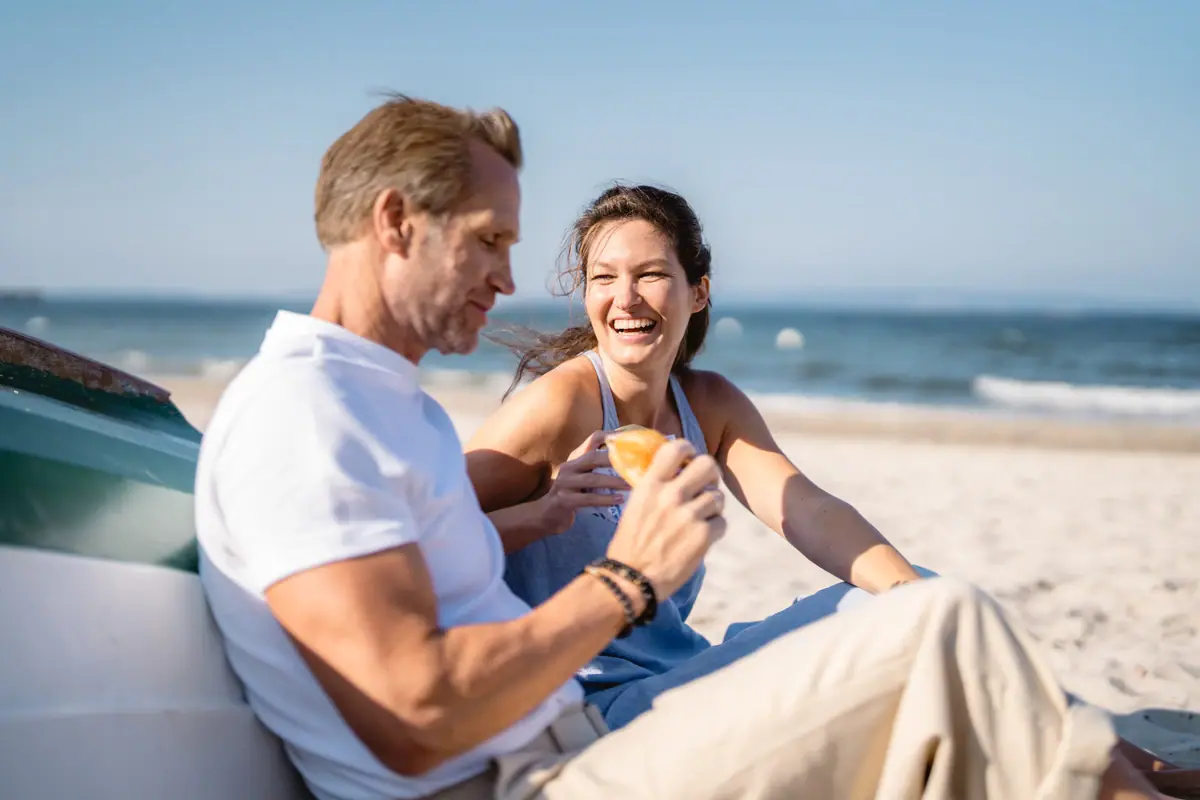 Un uomo e una donna sono seduti sulla spiaggia.