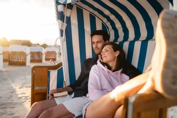 Paar im Strandkorb Ein Mann und eine Frau sitzen lächelnd auf in einem Strandkorb am Strand..