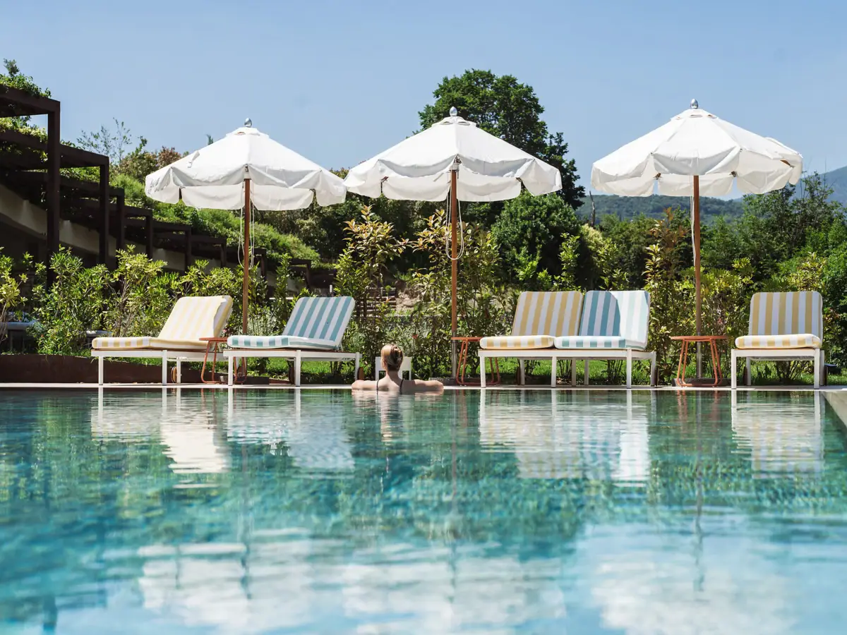 Piscina esterna dell’Hotel A-ROSA Lago di Garda con lettini, ombrelloni e vista sul paesaggio verde circostante.