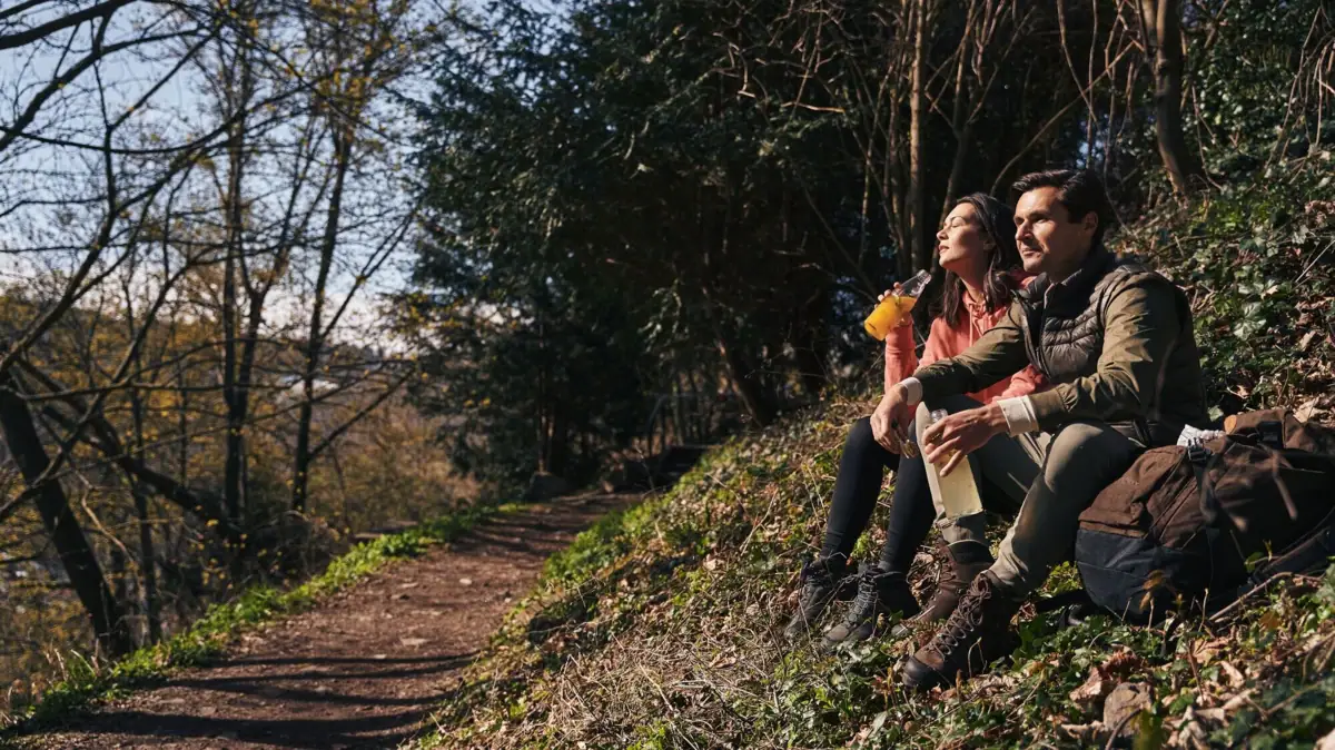 Ein Mann und eine Frau sitzen auf einem Felsen auf einem Wanderweg.