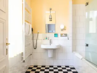 Un piccolo bagno con lavabo, doccia e pavimento in piastrelle bianche e nere.