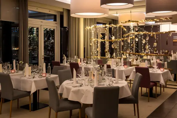 Capodanno a Sylt all’A-ROSA Una sala dell'hotel A-ROSA con tavoli e sedie, allestita per la notte di Capodanno a Sylt.