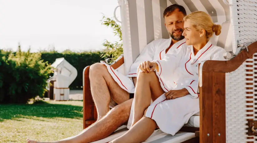 Un uomo e una donna sorridenti seduti su una sedia all'aperto.