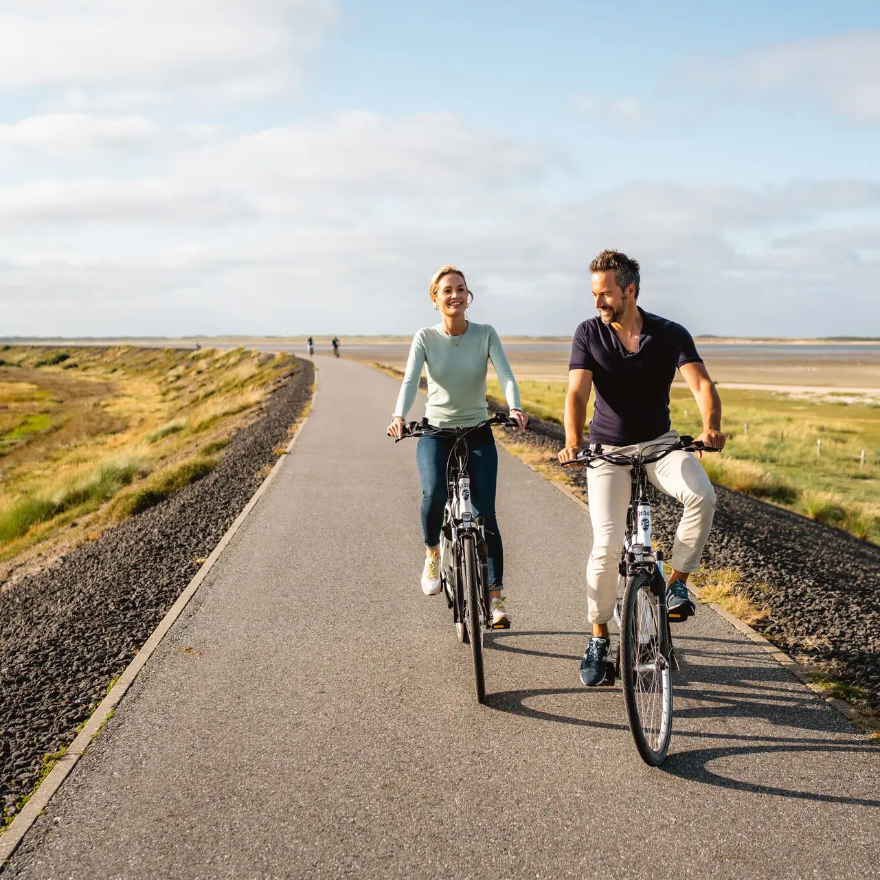 Un uomo e una donna vanno in bicicletta sulla diga di Sylt.