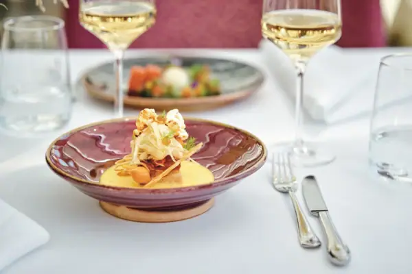 Restaurant Belvedere Ein Teller mit Essen auf einem Tisch, begleitet von einem Weinglas.