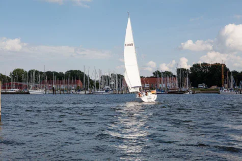 Un'imbarcazione a vela naviga sul lago sotto un cielo nuvoloso.