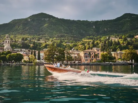 Barca sul lago di Garda circondata da montagne e nuvole.