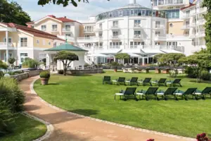 Sedia a sdraio in giardino con alberi e cielo sereno sullo sfondo.