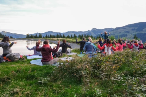 Un gruppo di persone sedute sull'erba vicino a un lago.