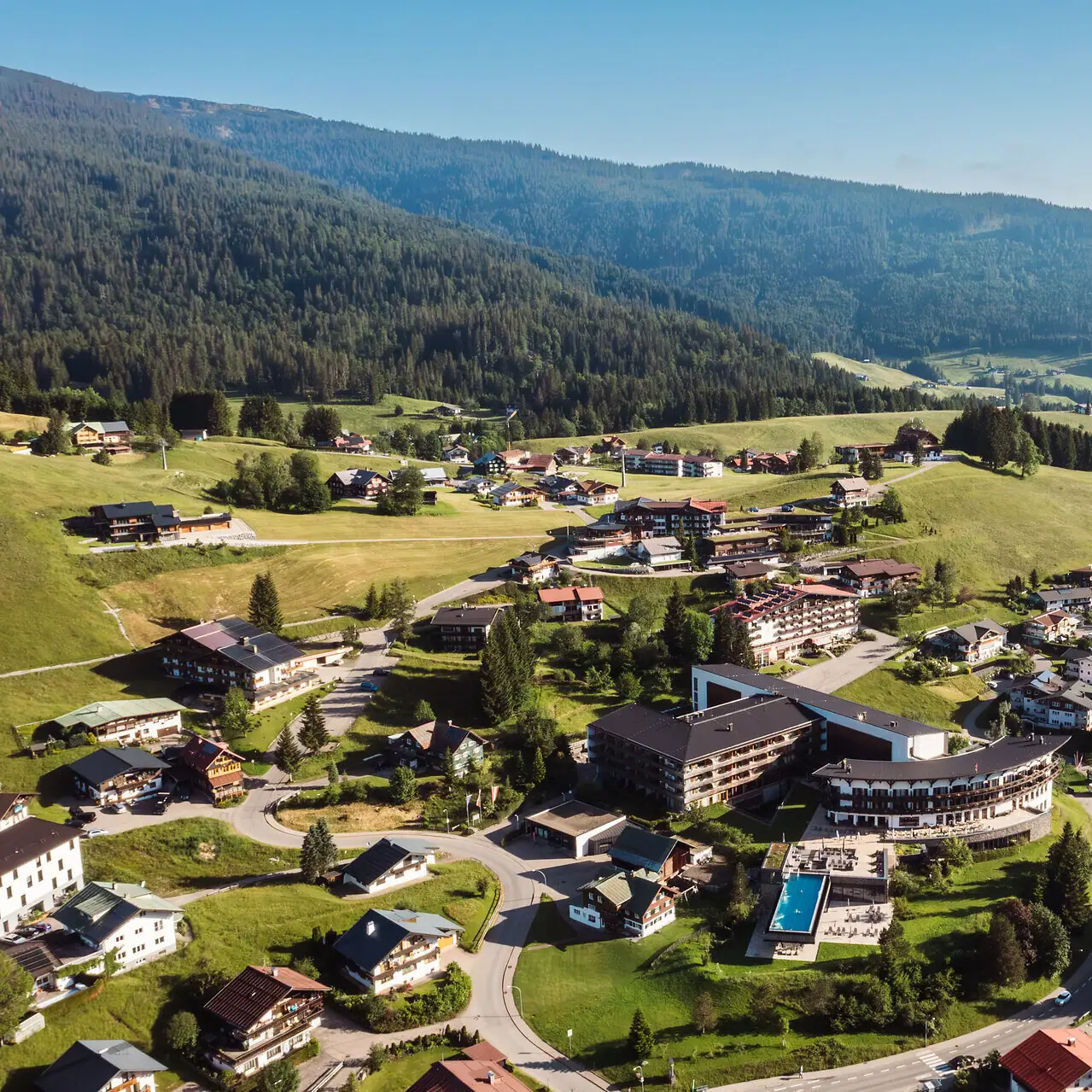 Ifen Hotel Kleinwalsertal Villaggio di montagna circondato da alberi e colline, visto dall'alto.