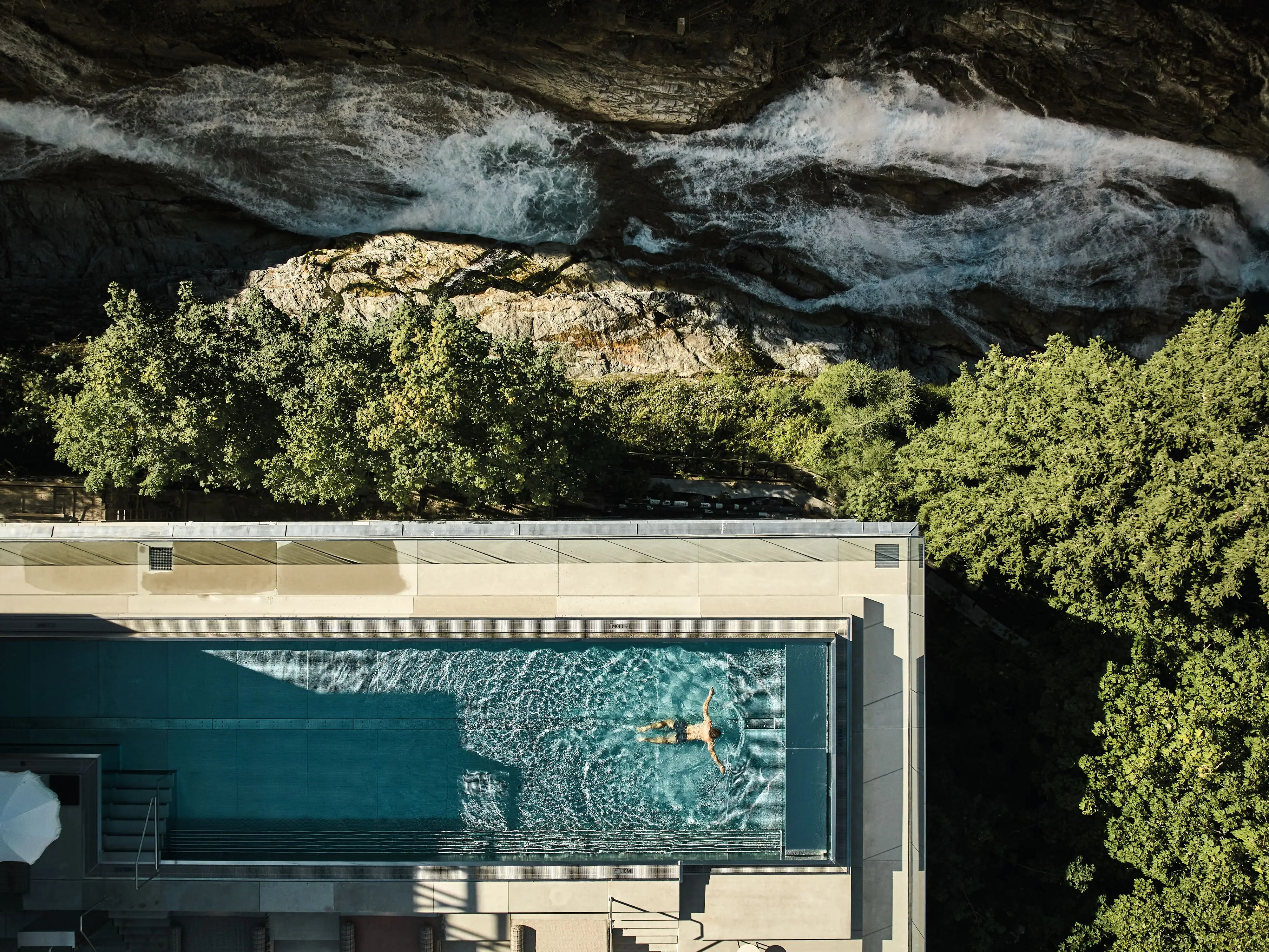 Eine Person schwimmt in einem Außenpool.