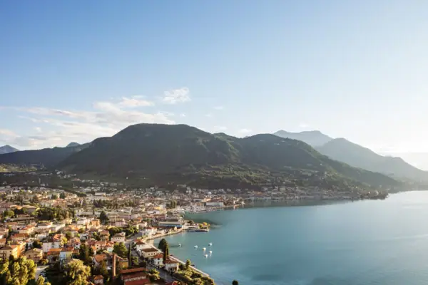 Gardasee von oben Stadt am Ufer eines Sees mit Bergen im Hintergrund.