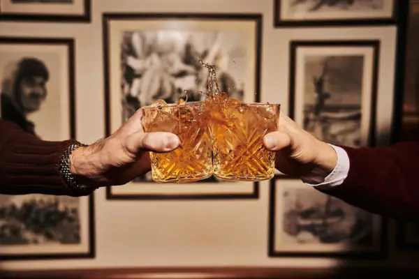 Club Bar Zwei Hände halten Gläser, aus denen Flüssigkeit spritzt.