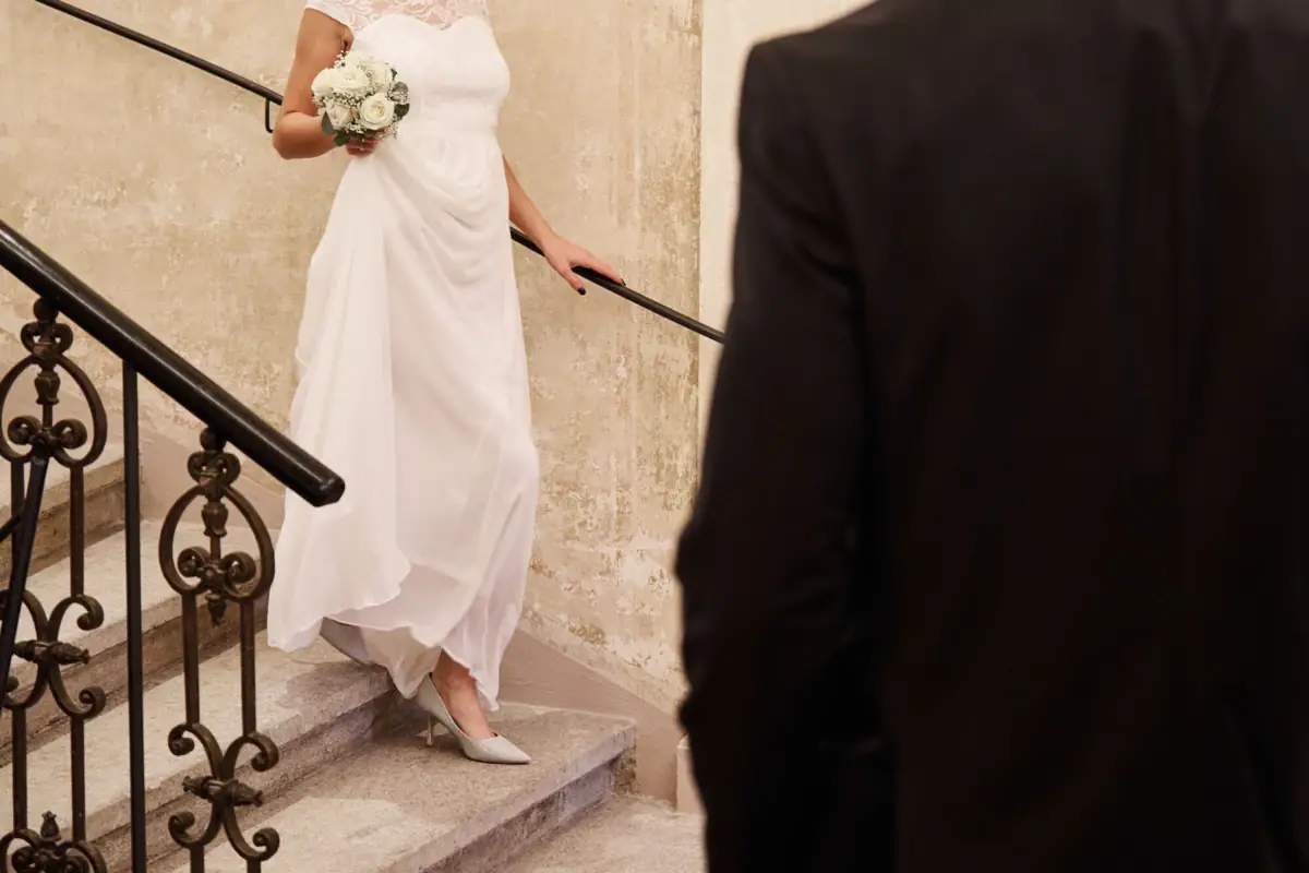 Una sposa in abito bianco con un bouquet di fiori che sale le scale.