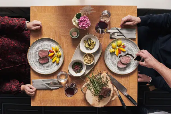 Eine Gruppe von Menschen sitzt an einem Tisch mit Tellern voller Essen.