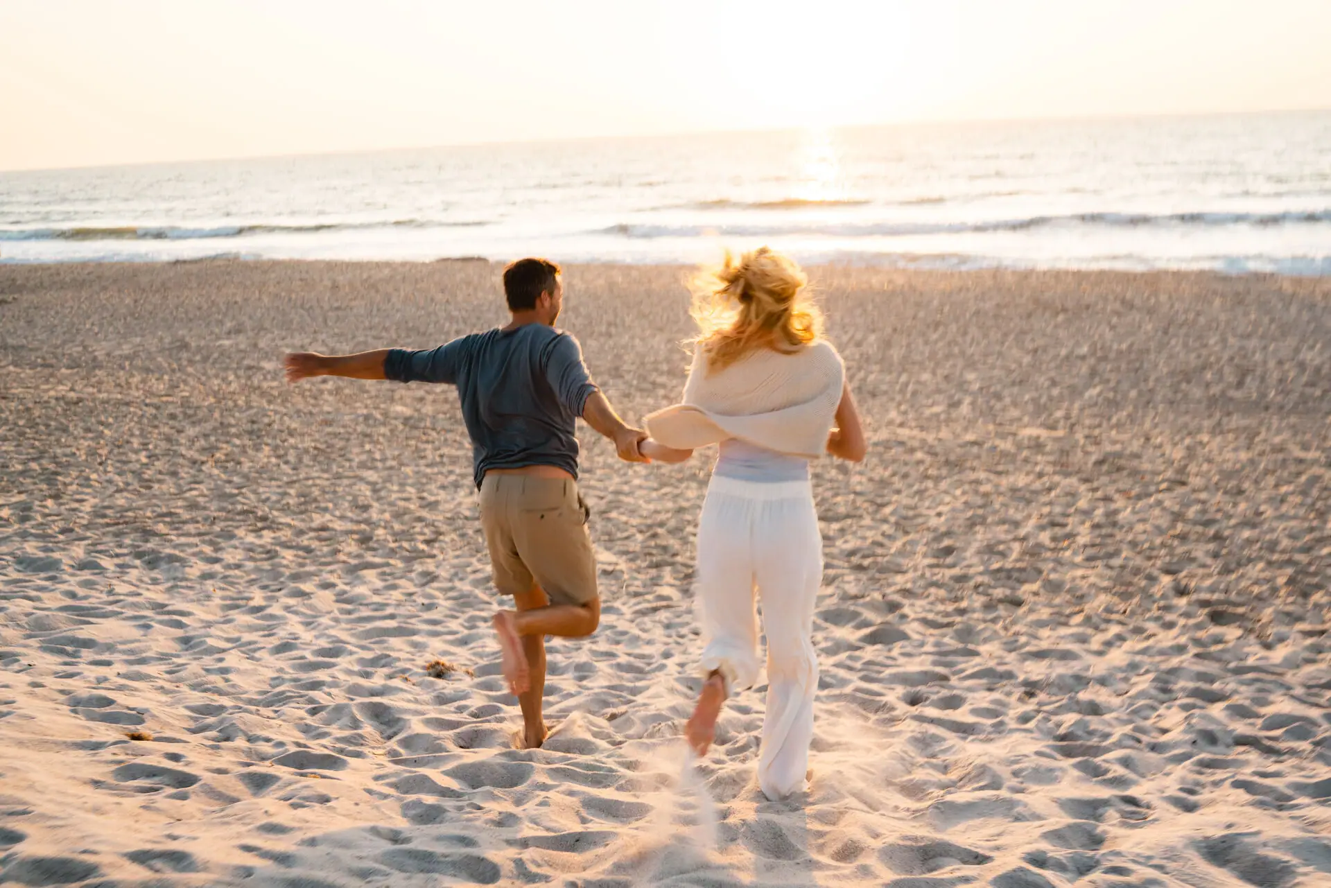 Ein Mann und eine Frau laufen am Strand.