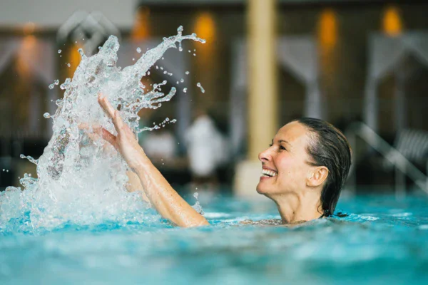 Donna che nuota in piscina con schizzi d'acqua.