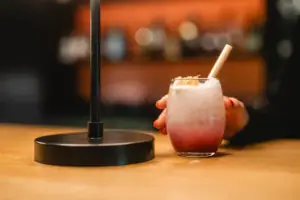 Una mano regge un drink con cannuccia e set da cocktail.