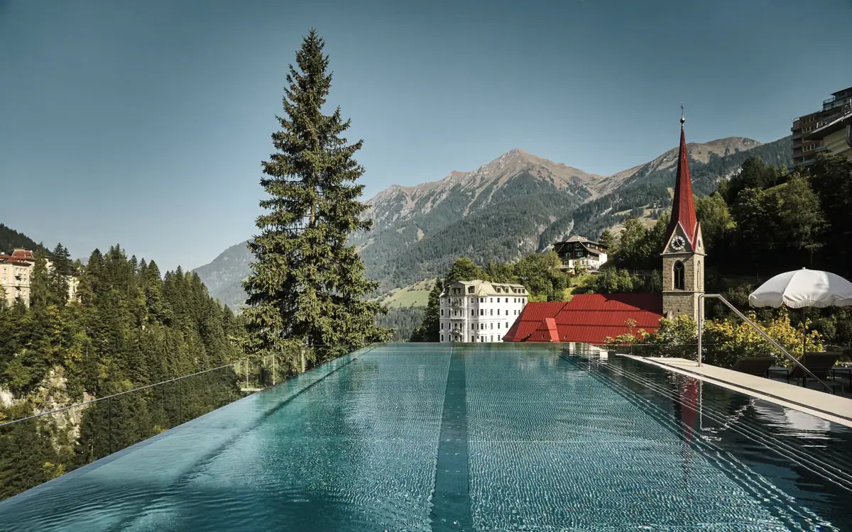 Una piscina con un edificio e le montagne sullo sfondo.