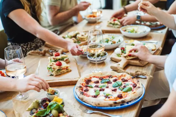 Festlich gedeckter Tisch mit italienischen Speisen, Pizza und Antipasti in geselliger Runde.