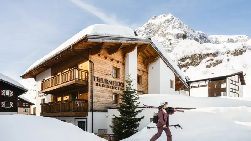 Residenzen Eine Person geht im Schnee mit Skiern.