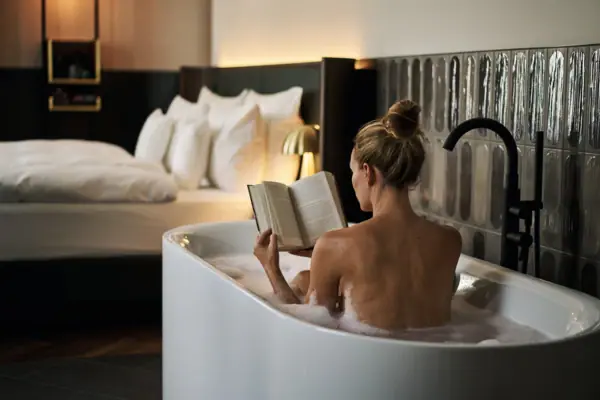 Una donna nella vasca da bagno sta leggendo un libro.