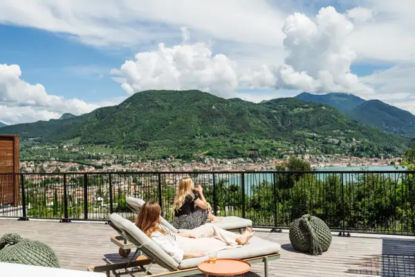 Due donne sedute su una terrazza con vista su un corpo d'acqua.