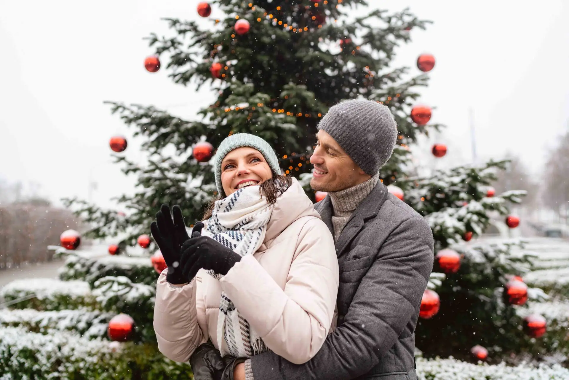 Un uomo e una donna sono in piedi davanti a un albero di Natale.