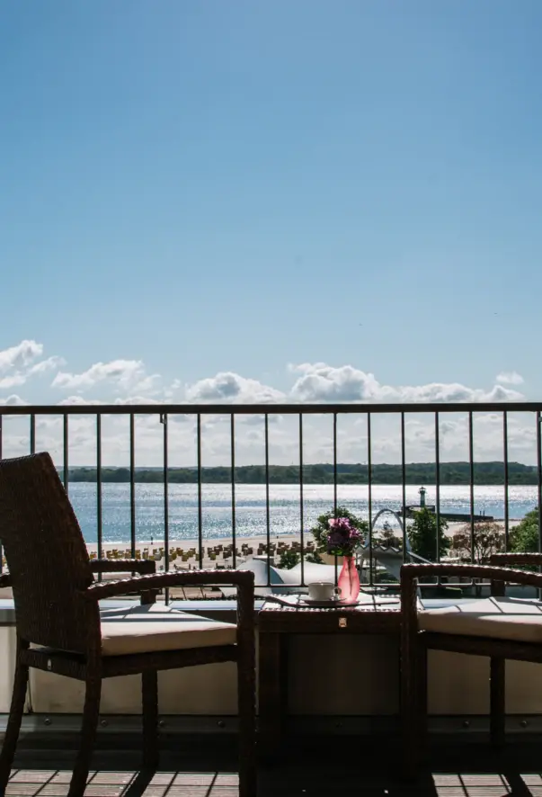 Tavolo e sedie su un balcone con vista sull'acqua.