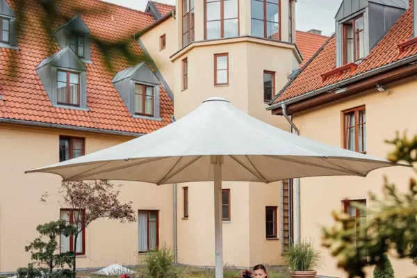 Una donna siede a un tavolo sotto un ombrellone nel cortile.