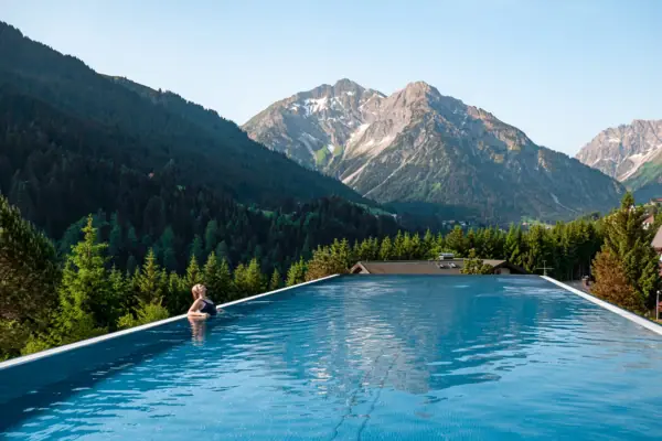 Una persona in una piscina con le montagne sullo sfondo.
