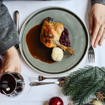 Una persona tiene un bicchiere di vino accanto a un piatto di cibo.