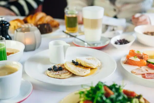 Frühstück Ein Teller mit Pfannkuchen, garniert mit Blaubeeren und Puderzucker.