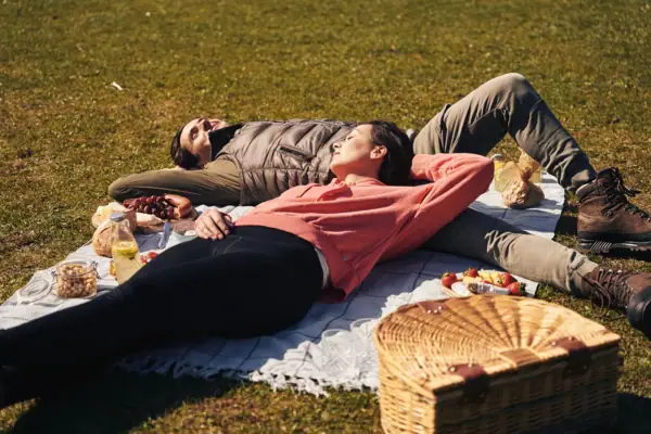 Ein Mann und eine Frau liegen auf einer Decke im Park.