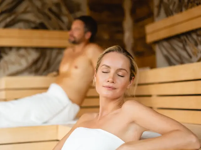 Donna sorridente seduta in una sauna.