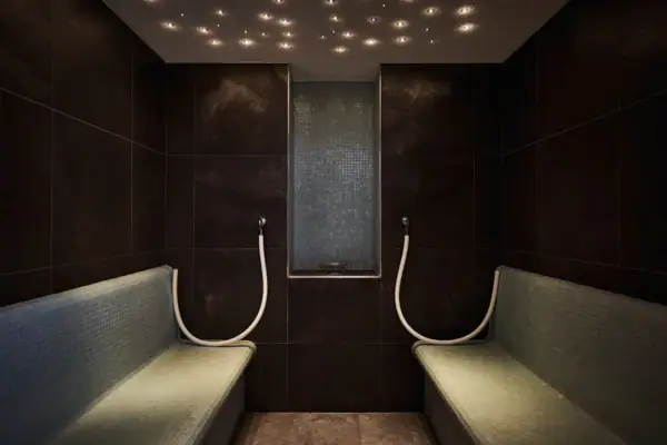 Duschraum mit Bänken und Fenster, gefliest mit hellen Wänden.