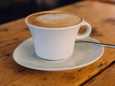 Tazza di caffè su un piattino, posata su un tavolo.