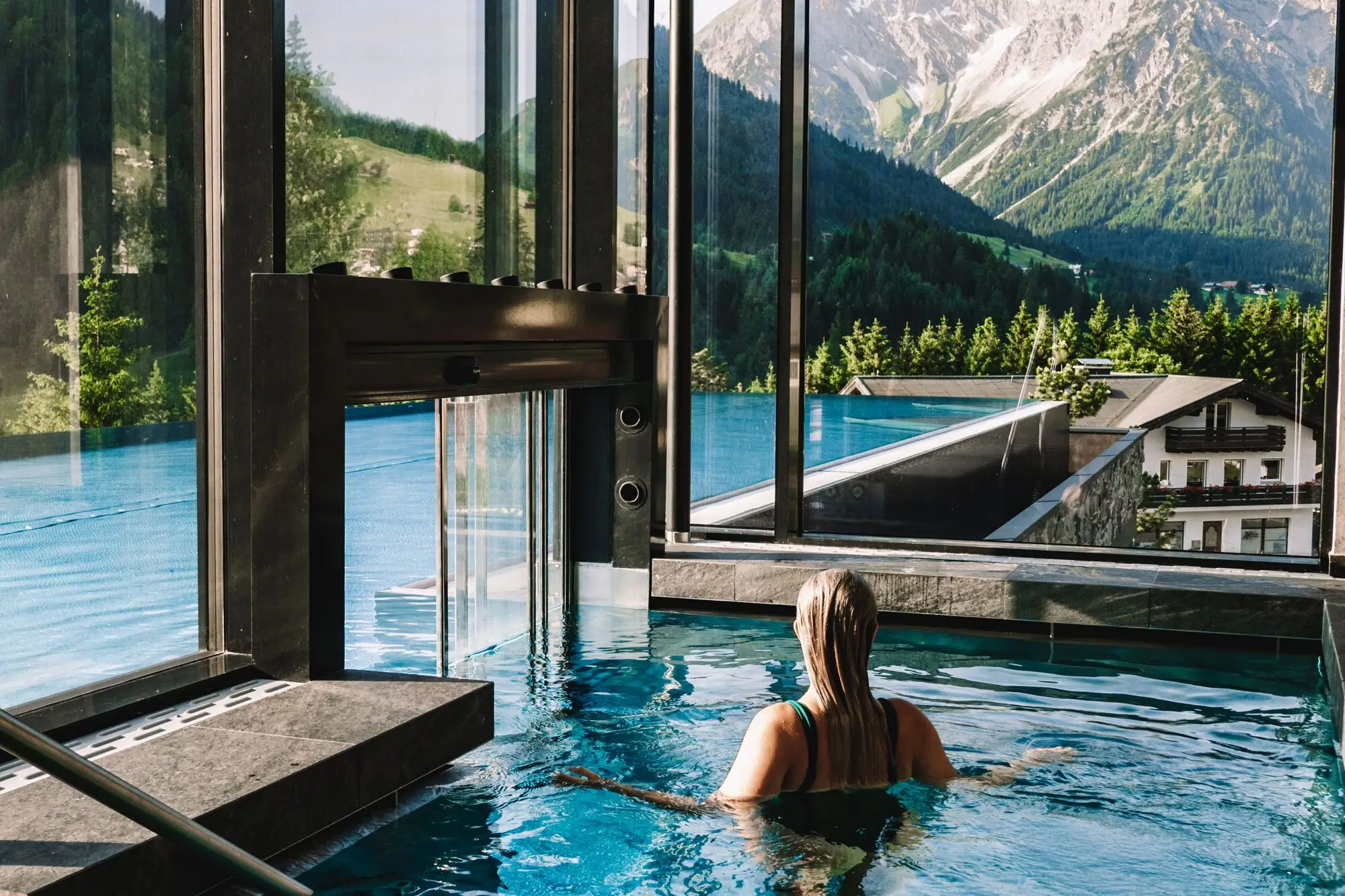 Una donna in piscina con vista su montagne e alberi