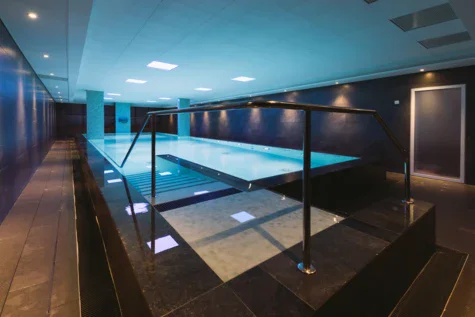 Piscina coperta con corrimano, soffitto visibile.