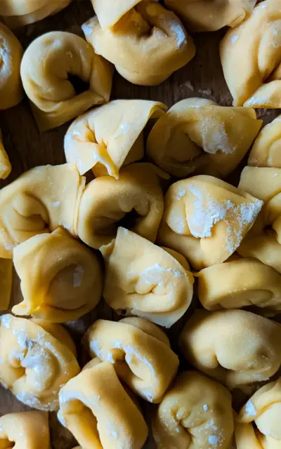 Pila di tortellini su una superficie di legno.