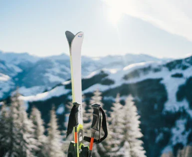 Un paio di sci e bastoncini sulla neve di fronte a una montagna innevata.