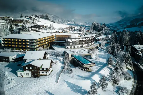Paesaggio innevato con l’A-ROSA Ifen Hotel Kleinwalsertal e gli alberi.