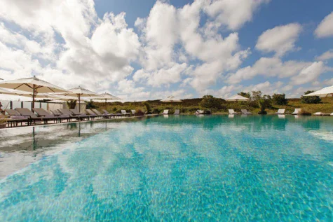 Piscina all'aperto con sedie e ombrelloni.