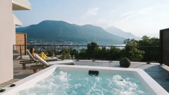 Donna seduta su una terrazza con una vasca idromassaggio che si affaccia sulla città.