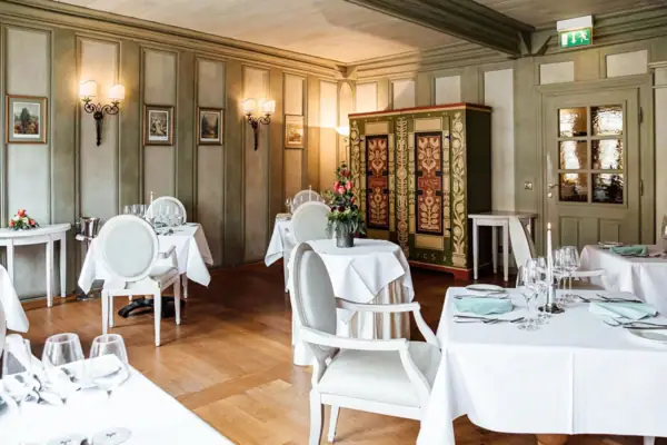 Ein Raum mit Tischen und Stühlen, elegant eingerichtet mit Tischdecken und Geschirr.