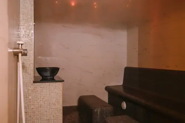 Ein gefliestes Dampfbad mit einer Bank und einer Schale.